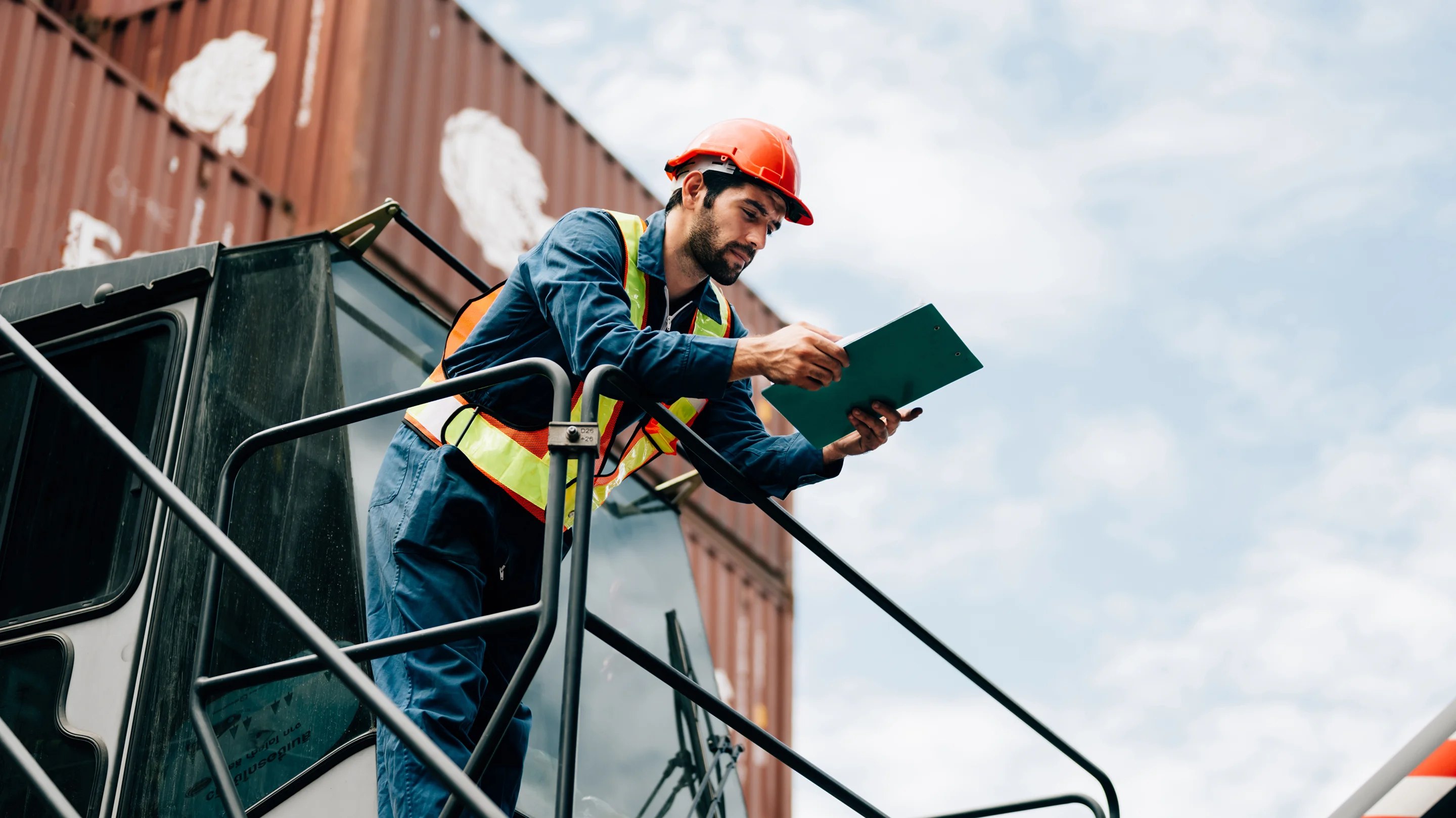 Operador logístico revisando documentación en puerto con contenedores de importación desde China
